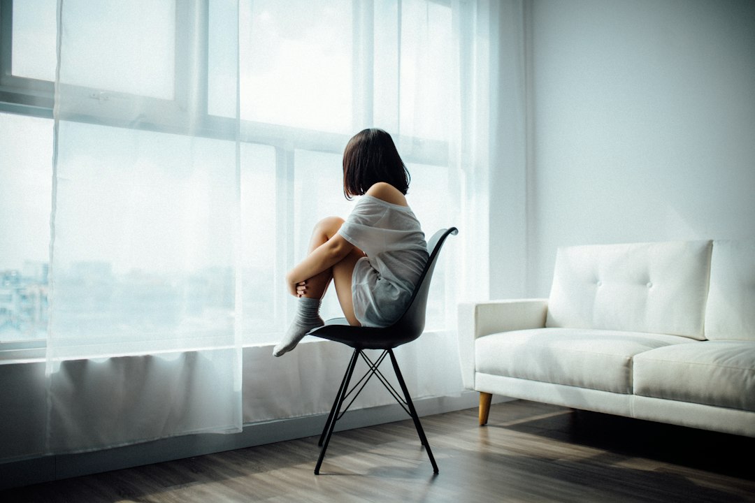 Mujer sentada junto a una ventana en una habitación luminosa