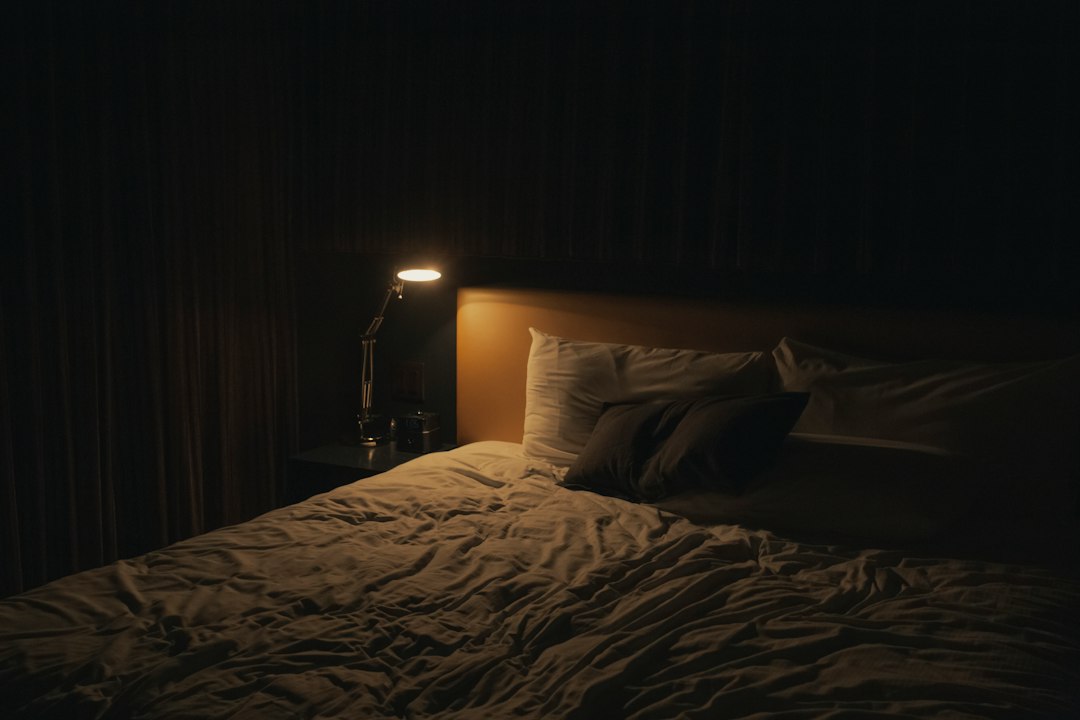 Cama y almohadas en un dormitorio con luz de mesilla